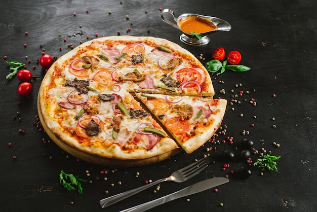 Pizza à la viande savoureuse avec divers ingrédients sur fond noir