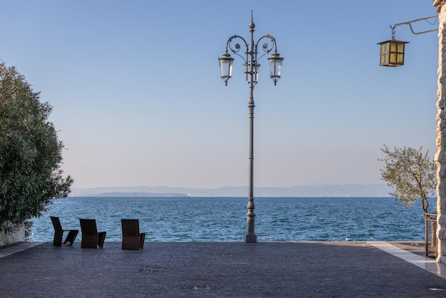 Photo place au bord de l'eau lazise ville chaises métalliques lampadaire lac de garde vue sur l'italie