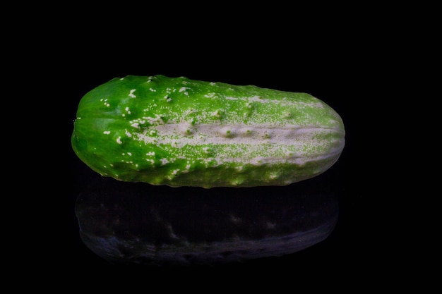 Une place de concombre vert à table miroir sur fond noir