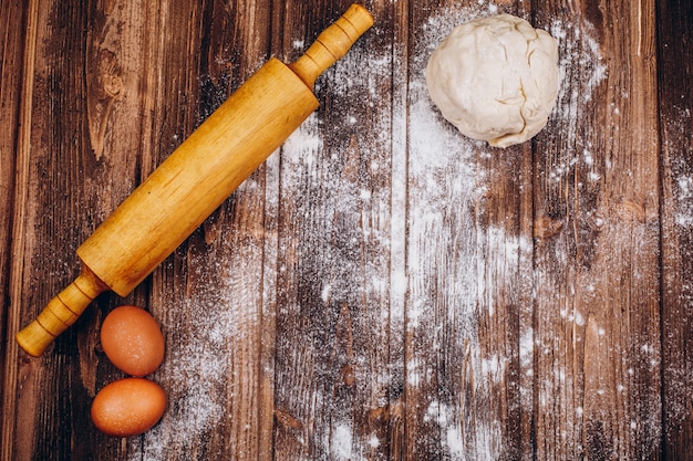 Placez sur la table en bois avec le rouleau à pâtisserie, la pâte, les oeufs et la farine pour la cuisson de la pâte de Noël