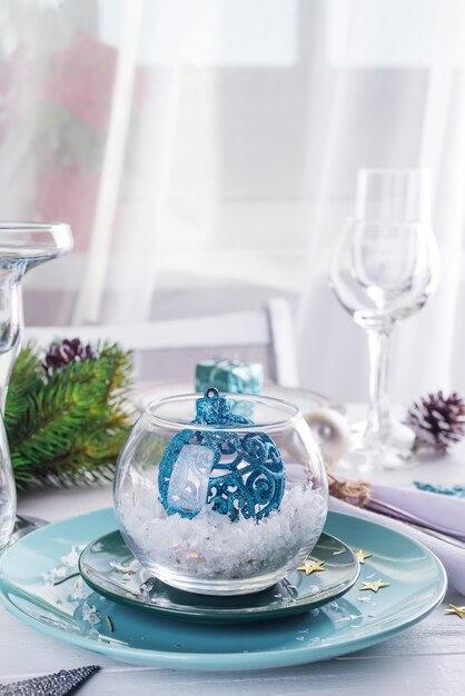 Placez la table pour table blanche de Noël avec des éléments de décor bleus avec des branches vertes arbre de Noël