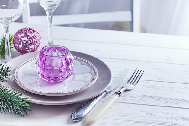 Placez la table pour table blanche de Noël avec des éléments de décor violet avec des branches vertes arbre de Noël