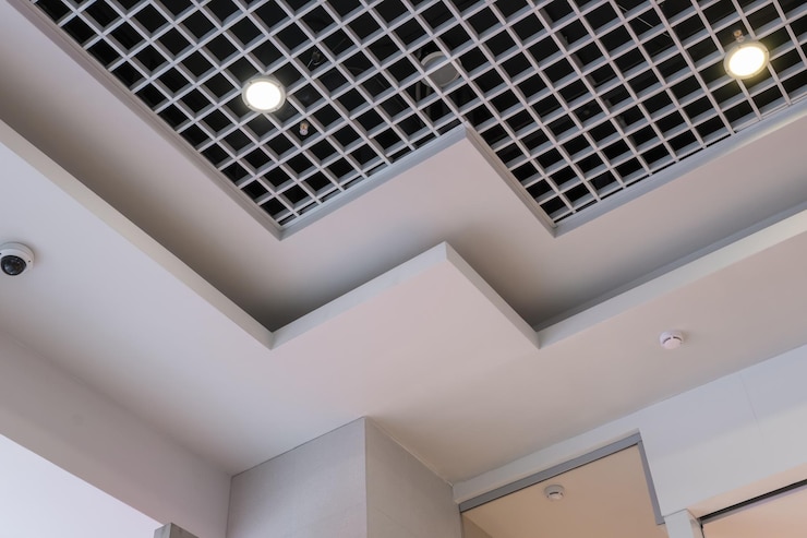 Photo plafond suspendu et grillagé avec lampes halogènes et construction de cloisons sèches dans une pièce vide d'un magasin ou d'une maison plafond tendu blanc et de forme complexe