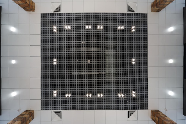 Plafond suspendu et grillagé avec spots halogènes et construction de cloisons sèches dans une pièce vide du magasin ou de la maison Plafond tendu blanc et de forme complexe avec climatisation et ventilation