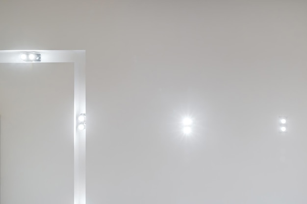 Plafond suspendu avec lampes à diodes led et construction de cloisons sèches dans une pièce vide d'un appartement ou d'une maison Plafond tendu blanc et de forme complexe