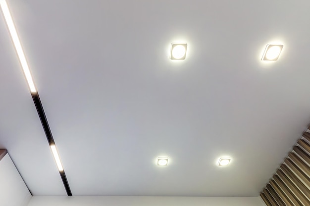 Plafond suspendu avec lampes halogènes et construction de cloisons sèches dans une pièce vide d'un appartement ou d'une maison Plafond tendu blanc et de forme complexe