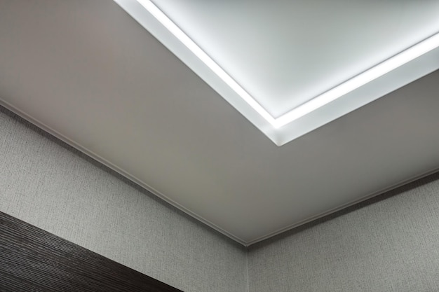 Plafond suspendu avec lampes halogènes et construction de cloisons sèches dans une pièce vide d'un appartement ou d'une maison Plafond tendu blanc et de forme complexe