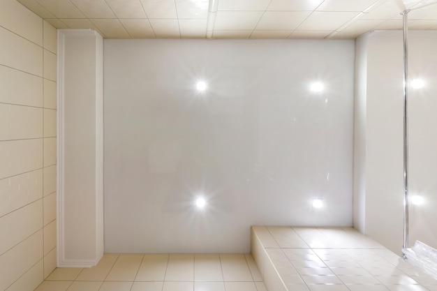 Plafond tendu blanc et forme complexe avec spots halogènes et construction de cloisons sèches dans une pièce vide d'un appartement ou d'une maison Plafond suspendu