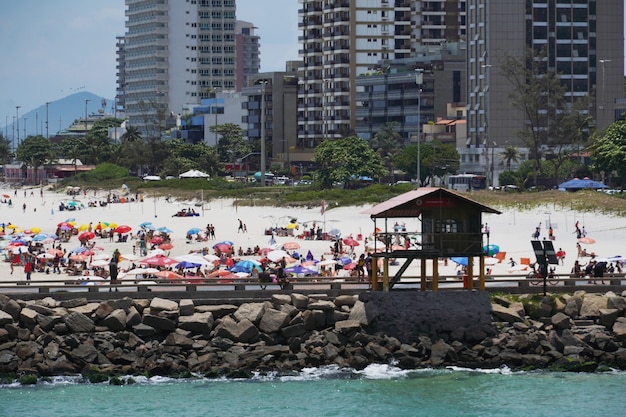 Plage de Barra da Tijuca par une journée ensoleillée avec des gens profitant du sable et de la mer. Vue sur le brise-lames, le canal de Barra et Praia dos Amores. Rio de Janeiro, RJ, Brésil. février 2021.