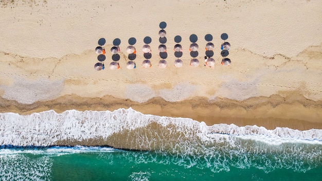 Plage avec beaucoup de parasols et transats, vagues de la mer Égée