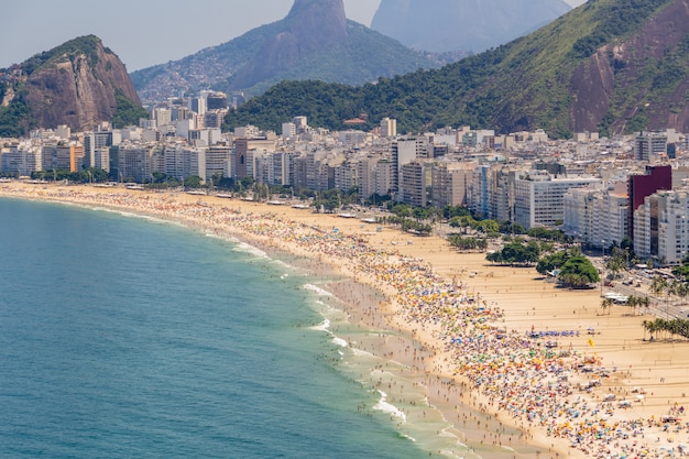 Plage de Copacabana pleine un dimanche ensoleillé typique à Rio de Janeiro.