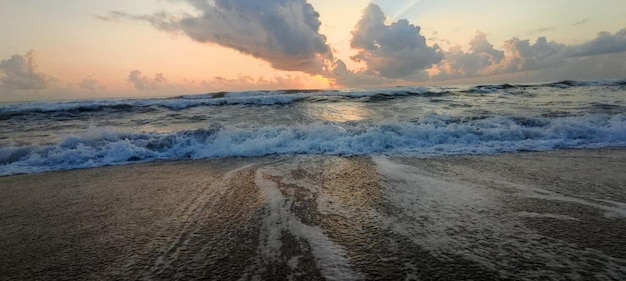 Une plage avec un coucher de soleil et un ciel nuageux Une belle mer