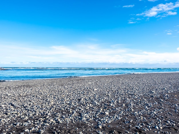 Plage de diamants de sable noir avec vagues et montagnes enneigées en hiver en Islande