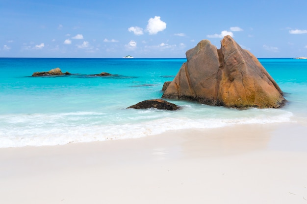 Plage avec eau bleue et ciel bleu et sable blanc et quelques rochers