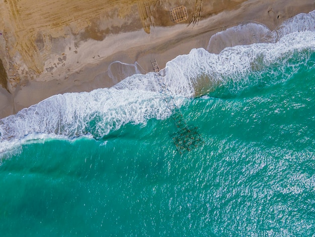 Une plage avec une eau bleue et un grand nombre de rochers sur le sable