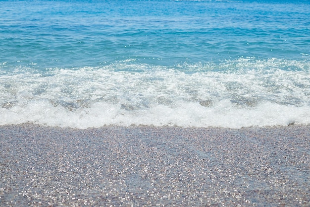 Plage de galets avec fond de texture d'eau de mer azurEau de mer claire sur une plage de galets eau pure sur le rivage de pierrelittoral avec rivage lapidémagnifique paysage marinvacances au paradis d'été