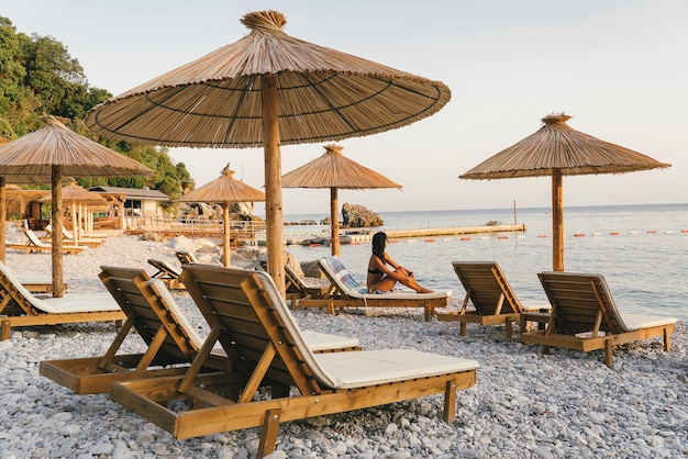 Plage de galets avec hamacs et parasols au coucher du soleil