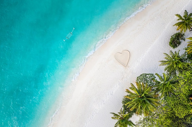 Plage de l'île tropicale, forme de coeur dans les palmiers de sable. Amour romantique idyllique et voyage d'été en lune de miel