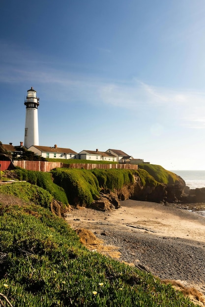 une plage avec des maisons sur le côté et un phare à droite