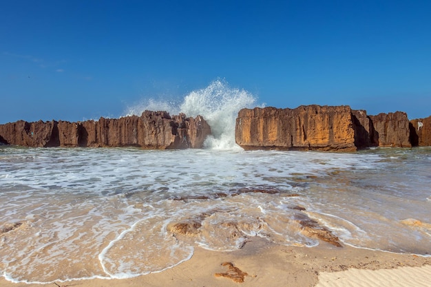 Une plage majestueuse avec des falaises imposantes, une eau bleue immobile et un ciel clair