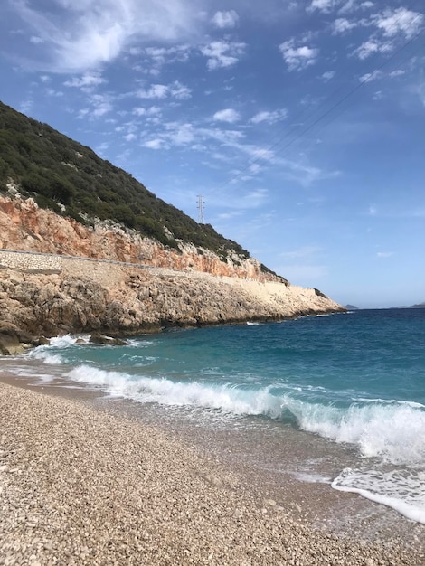 Une plage avec une mer bleue et une plage de galets avec une petite île en arrière-plan