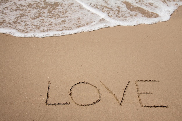 Une plage avec le mot amour écrit dans le sable