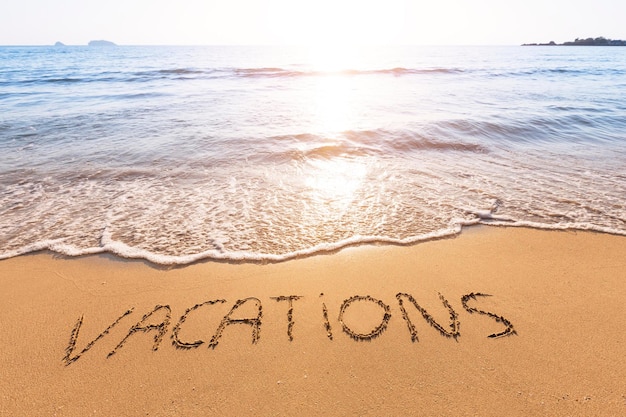 Une plage avec le mot vacances écrit dans le sable