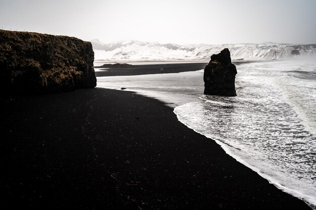 Photo la plage noire d'islande reynisfjara à vik depuis le point de vue de dyrholaey dyrholaay la côte de la plage de sable noir en islande arnardrangur