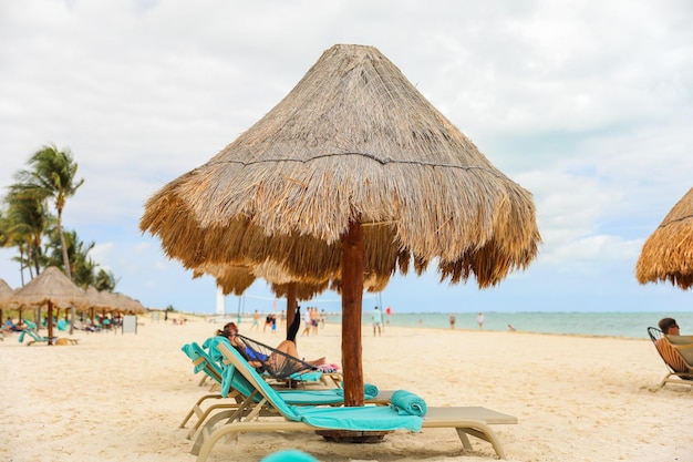 Une plage avec un parasol en chaume dessus