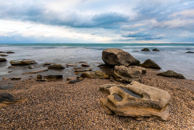 Une plage avec des rochers et un ciel nuageux