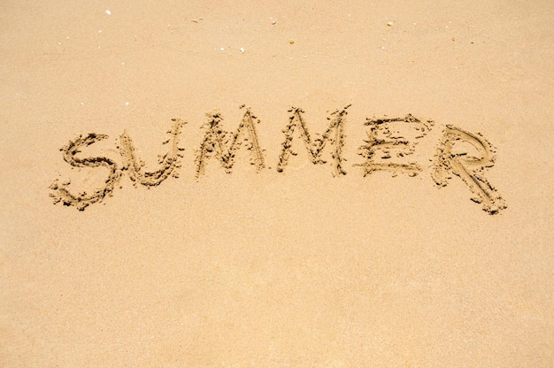 Plage de sable aux beaux jours avec texte été vacances fond de vacances Mot ÉTÉ dessiné avec une petite brindille par un touriste qui voyage à la mer