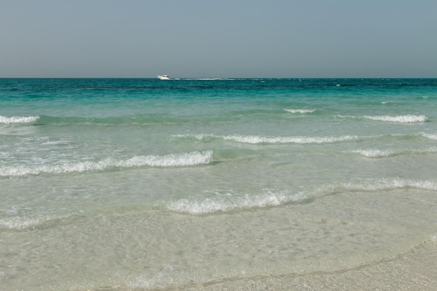 Plage de sable blanc bleu mer claire yacht eau vagues ciel clair