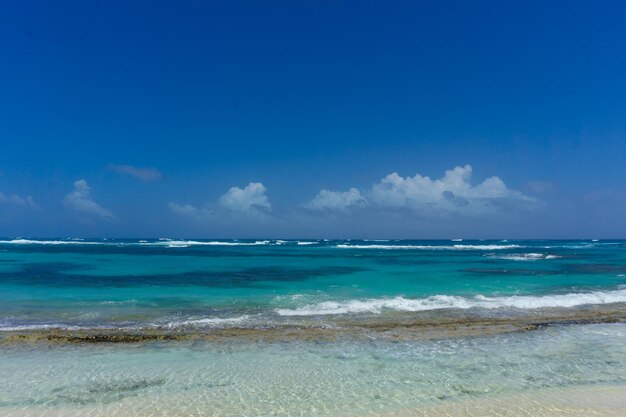 Plage de sable blanc idyllique avec des vagues venant de la mer pendant une journée venteuse
