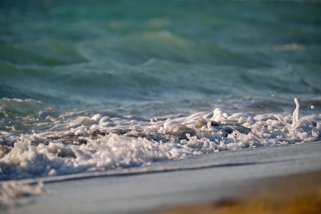 Plage de sable en bord de mer avec des vagues mousseuses s'écrasant sur le rivage