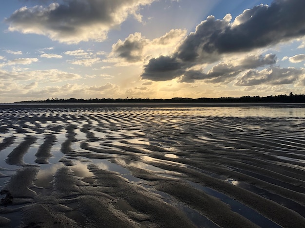 Plage de sable et d'eau reflétant le ciel Coucher de soleil