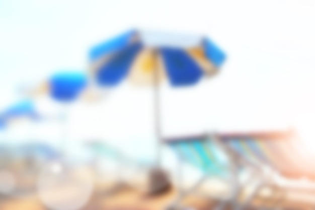 Plage de sable ensoleillée avec parasols et chaises floues - arrière-plan flou défocalisé