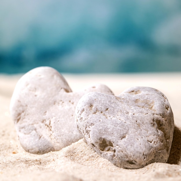 Plage de sable d'été avec des vagues et des pierres de coeur