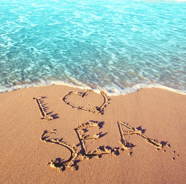 Photo plage de sable mer et l'inscription j'aime la mer meilleur concept de vacances
