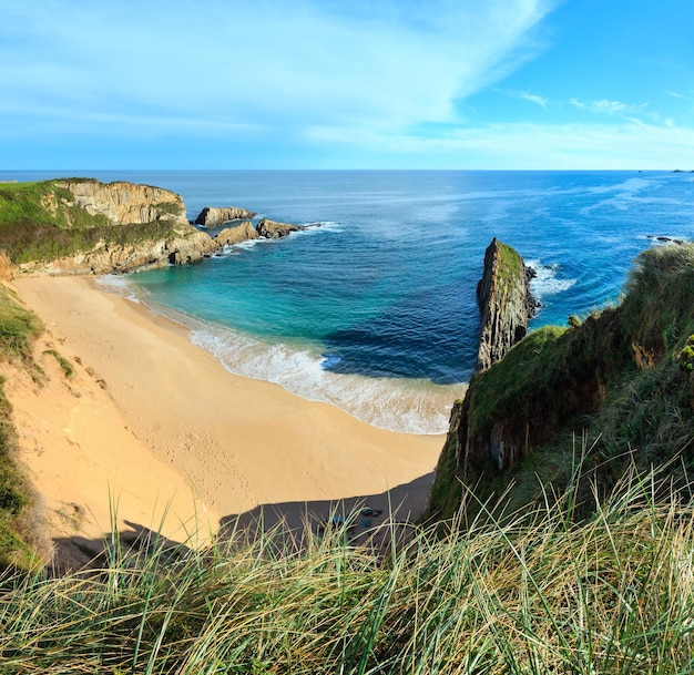 Plage de sable de Mexota et rocher pointu à proximité (Espagne). Paysage de littoral de l'océan Atlantique. Deux clichés piquent l'image.