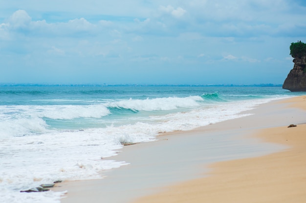 Une plage de sable tropicale idéale pour surfer sur l'océan. Belle eau turquoise claire et vagues.