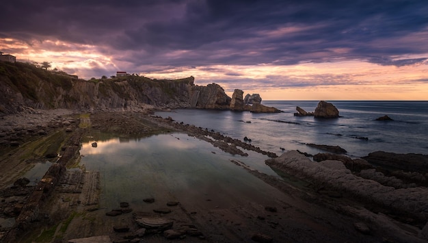 Plage située dans une baie avec une grande étendue de rainures dans la pierre et des corniches rocheuses frappantes dans la mer