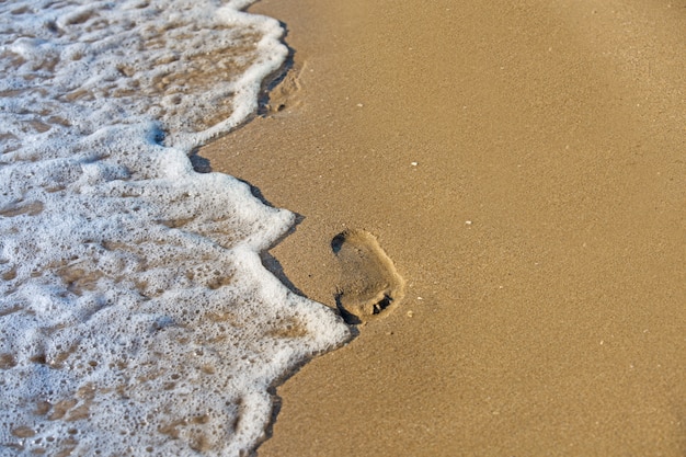 Plage, vagues et empreintes au coucher du soleil