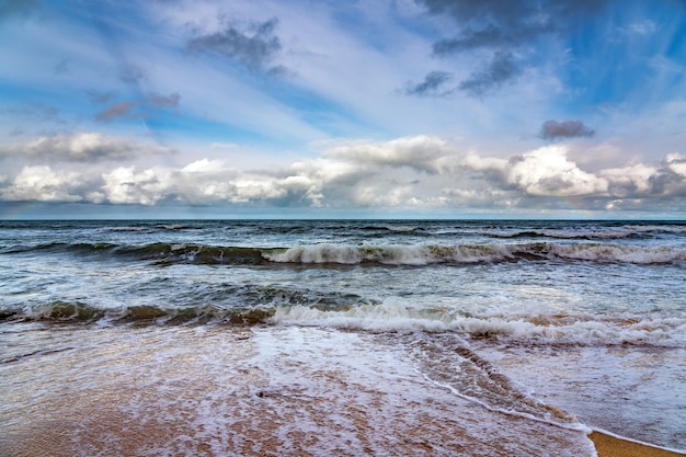 Plage vide et mer orageuse par temps nuageux