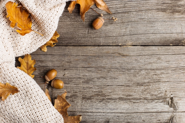 Plaid, feuilles et glands tricotés sur la vieille table en bois