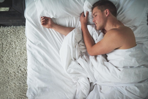 Le plaisir du sommeil Photo recadrée d'un jeune homme torse nu dormant dans sa chambre