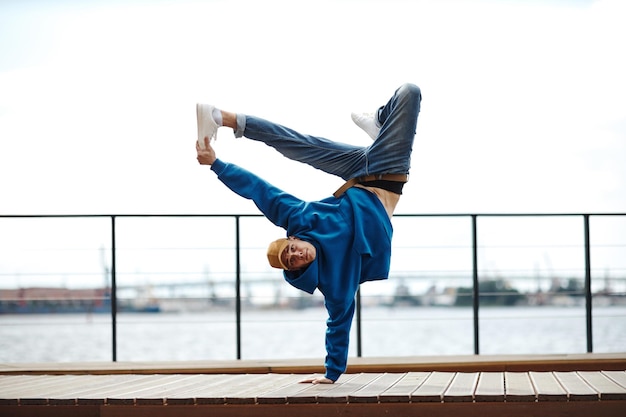 Plan d'action d'un jeune homme faisant une cascade de breakdance pose à l'extérieur contre l'espace de copie du ciel