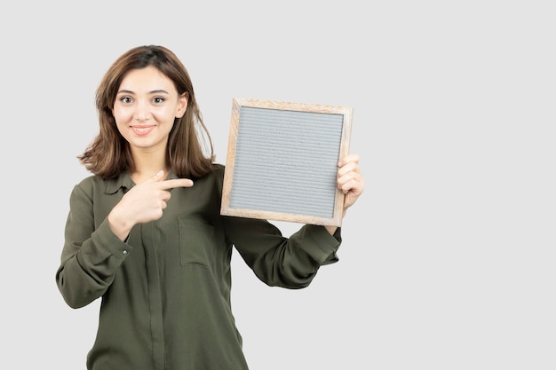 Plan d'une adorable jeune femme montrant un cadre vide sur blanc. photo de haute qualité