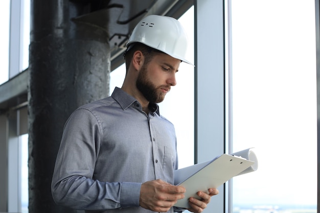 Plan d'un architecte portant un casque de sécurité et inspectant un nouveau bâtiment.