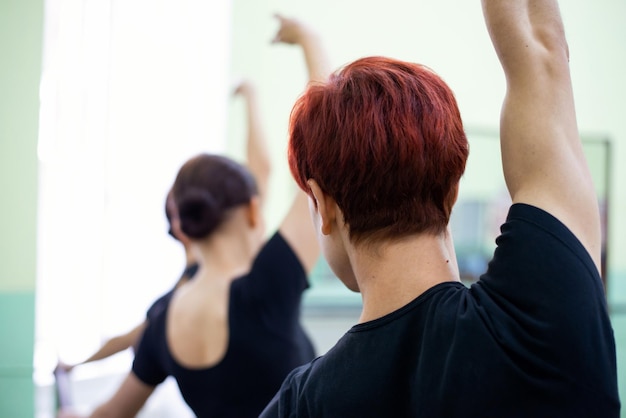 Plan arrière d'un groupe de danseurs ayant une leçon de chorégraphie apprenant de nouveaux mouvements