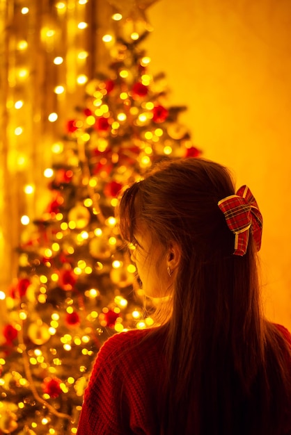 Plan arrière d'une jeune fille debout dans une salle décorée pour la fête de noël